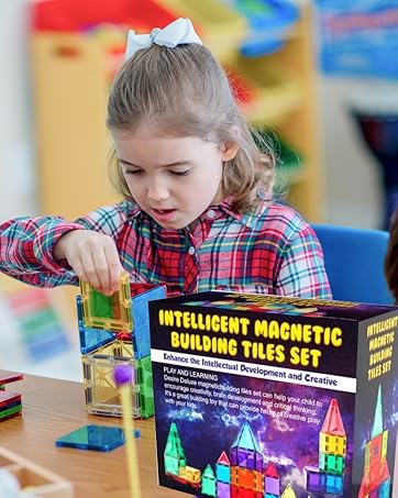 Child playing with colorful magnetic building tiles set, featuring transparent pieces in various geometric shapes.
