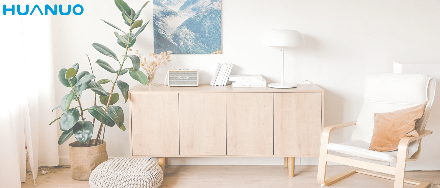 Modern living room with light wood sideboard, white armchair, potted plant, and wall art. Clean, minimalist interior design with natural elements.