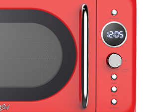 Red microwave oven with digital display showing 12:05. Features a black glass door, silver handle, and control buttons on the right side.
