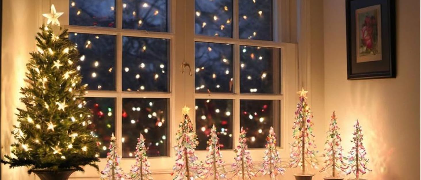 Festive living room scene with a lit Christmas tree, window showing snowy night, and decorative LED trees on a mantle with candles.