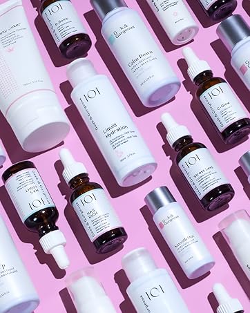 Array of skincare products on pink background. White and clear bottles with droppers and pumps, labeled with '101' branding.